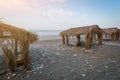 Several canopies with a reed roof stand in a row on the seashore