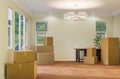 Several Cardboard Moving Boxes, Chair and Plant on Floor of Empty Room of House with Blank Wall Royalty Free Stock Photo