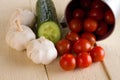 Several cherry tomatoes and garlic with cucumber on white board Royalty Free Stock Photo
