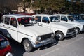 Several classic white Renault 4 cars parked in line with a granny inside