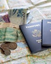 foreign coins falling onto two American passports and paper currency laying on large open map
