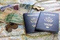 foreign coins and paper currencies from countries with two American passports laying on large open map