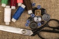 Several colored buttons of different sizes, reels of colored sewing thread, and large vintage sartorial scissors against a Royalty Free Stock Photo