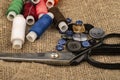 Several colored buttons of different sizes, reels of colored sewing thread, and large vintage sartorial scissors against a Royalty Free Stock Photo