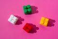 Several colored details cubes of a children`s constructor on a pink background