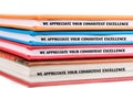 Several colorful binders stacked neatly on a surface, each praising consistent excellence in performance. The layout