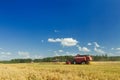 Several combine harvesters working on oats farm field under blue sky during hot summer day Royalty Free Stock Photo