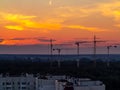 Several construction cranes on the background of colorful sunset sky