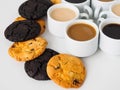 Several cups of coffee, vanilla and chocolate raisin cookies on a white table. The modern concept of food. Palette of shades of