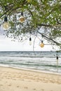Edison lamps hanging on cables on green tree on sand beach Royalty Free Stock Photo
