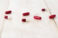 Different red and white drug capsules for ingestion. A close-up on a bright wooden table Royalty Free Stock Photo