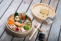 Several different traditional Chinese dimsum dumplings in a wooden basket cooked for guests on a wooden table in a
