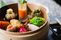 Several different traditional Chinese dimsum dumplings in a wooden basket cooked for guests on a wooden table in a