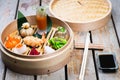 Several different traditional Chinese dimsum dumplings in a wooden basket cooked for guests on a wooden table in a