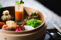 Several different traditional Chinese dimsum dumplings in a wooden basket cooked for guests on a wooden table in a