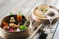 Several different traditional Chinese dimsum dumplings in a wooden basket cooked for guests on a wooden table in a