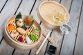 Several different traditional Chinese dimsum dumplings in a wooden basket cooked for guests on a wooden table in a