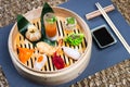 Several different traditional Chinese dimsum dumplings in a wooden basket cooked for guests on a wooden table in a