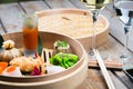 Several different traditional Chinese dimsum dumplings in a wooden basket cooked for guests on a wooden table in a