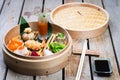 Several different traditional Chinese dimsum dumplings in a wooden basket cooked for guests on a wooden table in a
