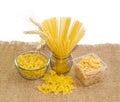 Several different uncooked pasta and wheat spikes on sackcloth Royalty Free Stock Photo