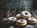 Several donuts sprinkled with powdered sugar from above, on a dark background. Sweet dessert, carbohydrates