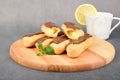 Several eclairs lie in a row and one cut eclair lies on top of them. A cup with lemon on the edge Royalty Free Stock Photo