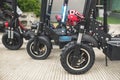 Several electric scooters parked by the side of a concrete road