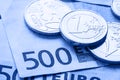 Several 500 euro banknotes and coins are adjacent. Symbolic photo for wealt.Euro coin balancing on stack with background of bankno Royalty Free Stock Photo