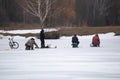 Several fishermen sit on boxes on the thin spring ice far from the shore and fishing. Royalty Free Stock Photo