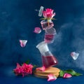 Several flasks are in the air. Levitation. Pink roses and flying petals. Mystical picture. Blue background, smoke