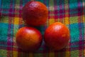 Several fresh red oranges have just been picked from a tree and piled on a checkered fabric of various bright colors. Royalty Free Stock Photo