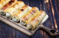 several fried spring rolls lie on a wooden board in a row