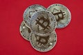 Several gold coins cash Bitcoin lie on red background, close-up.