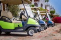 Several Golf cars are parked in the Parking lot. Electric cars for moving around the resort complex of a five-star hotel. A means Royalty Free Stock Photo