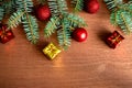Several green spruce branches with red Christmas balls, Christmas-tree decorations and small gifts on a wooden background. Flat Royalty Free Stock Photo
