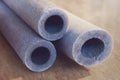 Several grey insulation for heating water pipes close-up. Industry, electrical on wood background Royalty Free Stock Photo