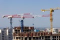 Several high-rise cranes at a construction site, together with people, are building a modern apartment building. Royalty Free Stock Photo