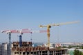 Several high-rise cranes at a construction site, together with people, are building a modern apartment building. Royalty Free Stock Photo