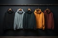 Several hoodies of different colors hang on a hanger on a dark background. Athleisure style
