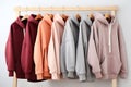 Several hoodies of different light pastel tones and colors hang on a hanger on a white background. Athleisure style