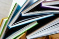 Several identical hardcover books with multicolored covers are stacked in each other, top view, selective focus