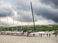 Several jacked sail boats on the beach in front of a dune.