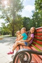 Several kids sitting on the bench in summer park Royalty Free Stock Photo