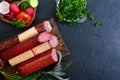 Several kinds of sausage, fresh vegetables and greens on a black background. Royalty Free Stock Photo