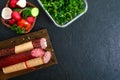 Several kinds of sausage, fresh vegetables and greens on a black background. Royalty Free Stock Photo