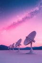 Several large satellite dishes stand in a row facing a pink and blue starry sky, representing space technologies and communication Royalty Free Stock Photo