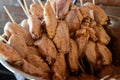 Several little chicken tulips, seasoned with salt, garlic, pepper, skewered on wooden sticks, inside a stainless steel basin