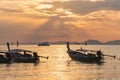 Local thai longtail motor boats under golden sun rays in the sea water at orange sunset in Ao Nang in Krabi Royalty Free Stock Photo