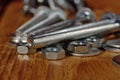 Several long screws for home workshop on a wooden surface. Shallow depth of field